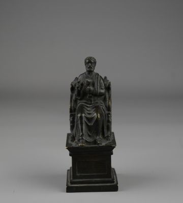 une statue en bronze représentant un homme assis sur une chaise