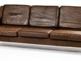brown leather sofa with black legs and arm rests on a white surface