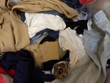 a pile of clothes sitting on a couch next to a pillow