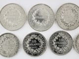 six different types of silver coins are arranged on a white surface