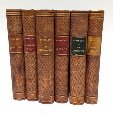 six vieux livres sont alignés sur une surface blanche