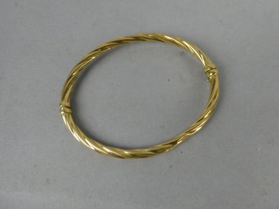 gros plan d'un bracelet en or sur une surface blanche