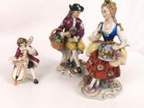 two figurines of women with baskets of flowers and a dog