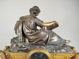 a statue of a man reading a book on top of a clock