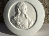une assiette blanche sur laquelle est représentée une femme