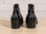 the back view of a pair of black ankle boots on a wooden table