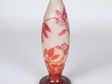 un vase rouge et blanc posé sur un socle, sur fond blanc