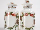 two white vases with flowers and leaves on them
