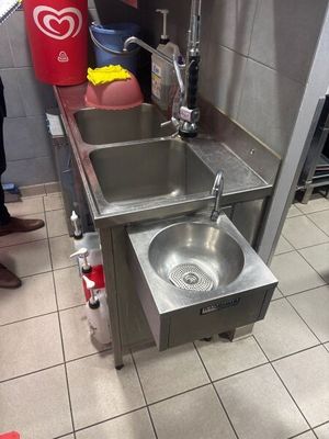 a kitchen with a sink and a trash can in it