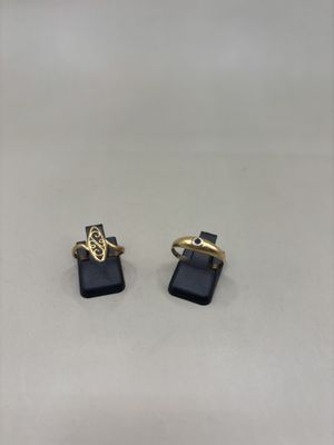 une paire de boucles d'oreilles dorées et noires posées sur une surface blanche