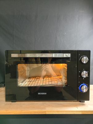 un four grille-pain noir posé sur un plan de travail en bois