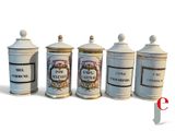 four white and gold canisters with labels on them on a white surface