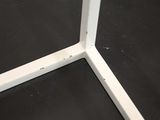 the corner of a white metal table with a black table top