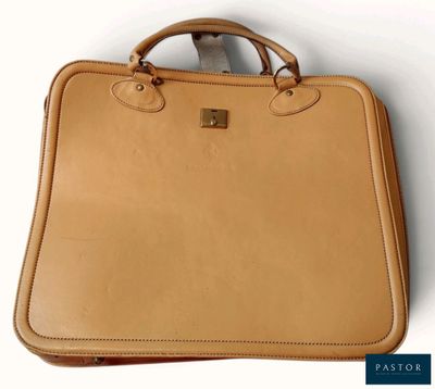 un gros plan d'une mallette en cuir beige posée sur une surface blanche