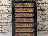a black and gold chest of drawers against a brick wall