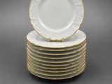 a stack of white and gold dinner plates with gold trim