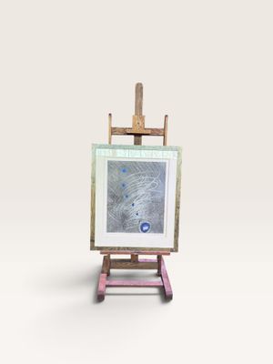 un petit chevalet sur lequel est posé un tableau, posé sur une surface blanche