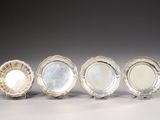 four silver plate dishes on stands on a gray surface