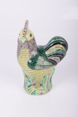 a green and yellow bird figurine sitting on a white surface