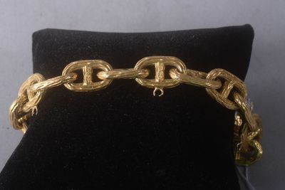 gold plated bracelet with chain links and clasps on a black velvet cushion