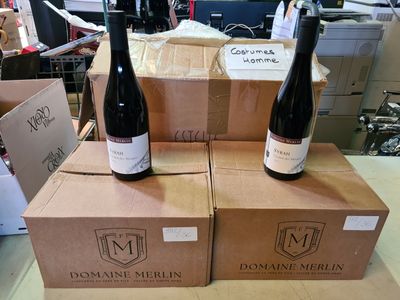 deux bouteilles de vin posées sur des cartons, eux-mêmes posés sur une table