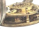 a close up of a silver clock with gears on it