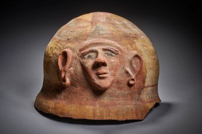 un gros plan d'un casque en argile sur lequel est représenté un visage