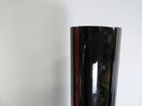 un grand vase noir posé sur une table près d'un mur blanc