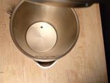 a metal bowl on a wooden table with a blender