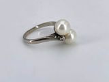 a close up of a white pearl ring on a white surface