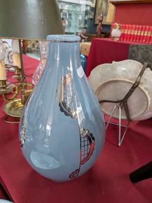 un vase bleu posé sur une table, sur laquelle se trouve une lampe