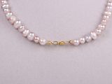 a pink pearl necklace with a gold clasp on a mannequin mannequin