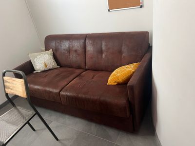 a brown leather couch sitting in a corner of a room