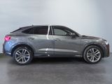 a grey audi suv parked in a showroom with a white wall