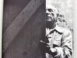 black and white photograph of an old man leaning against a wall