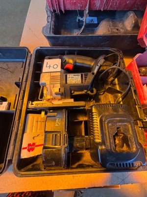 une boîte à outils contenant un marteau, une perceuse et d'autres outils, posée sur une table