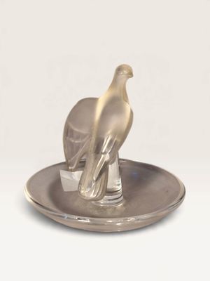 a silver plate with a bird on top of it on a white surface