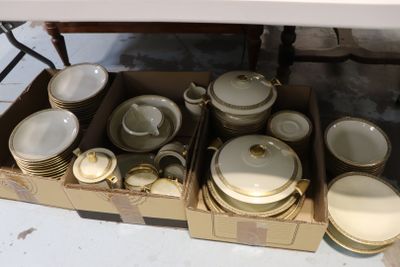 une boîte contenant de nombreux plats et bols blancs et dorés