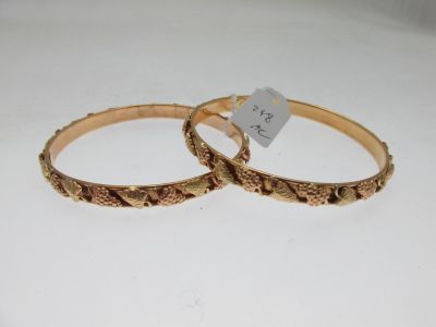 pair of gold tone bangles with engraved design on each side