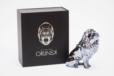 the silver lion figurine is next to a black box