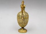an image of a gold vase with a bird on it