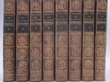 several old books are lined up in a row on a white surface