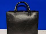 a black handbag sitting on top of a table next to a blue wall