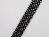 a close up of a black and silver bracelet on a white surface