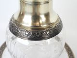 a glass vase with a metal handle on a table