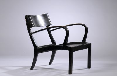 une chaise noire posée sur un sol blanc, près d'un mur
