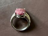 une bague sertie d'une pierre rose, posée sur une table