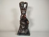 une statue en bronze d'une femme assise sur un rocher