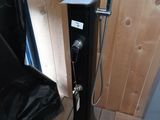 une douche posée sur un plancher en bois, à côté d'une chaise noire