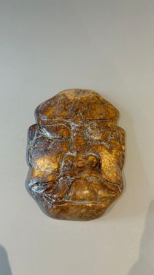 MASQUE en pierre dure sculptée dans les tons ocres.
